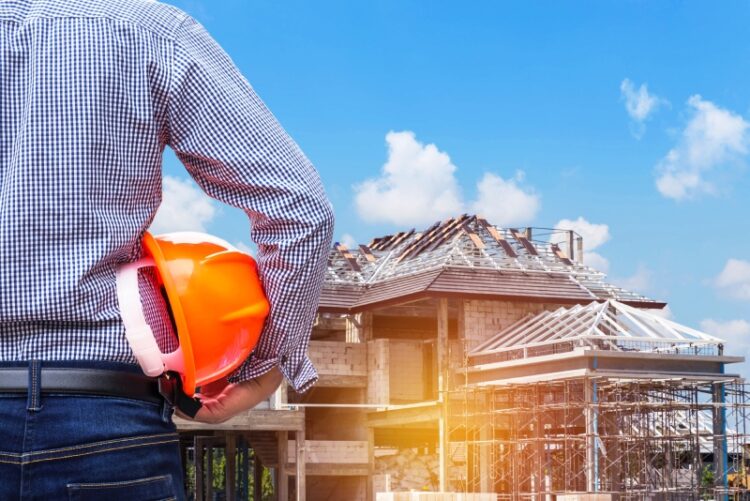 resident engineer holding yellow safety helmet at new home building under construction site